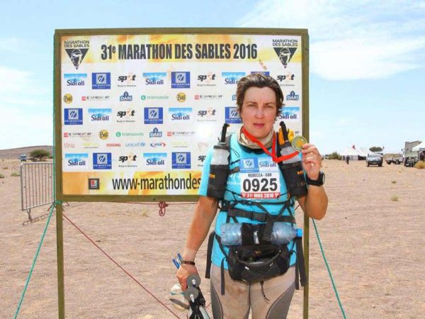 Fundraiser Bec Drackley in front of Marathon Des Sables finish banner