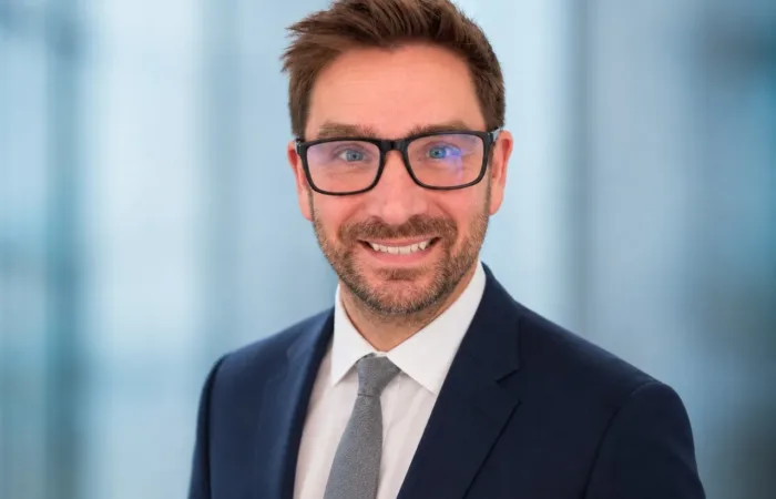 A photo of James Harcourt, the CEO for Working Animals International, smiling at the camera wearing glasses and a suit.