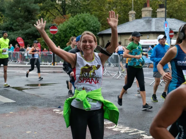 Woman celebrating SPANA run with arms raised at Royal Parks Half Marathon