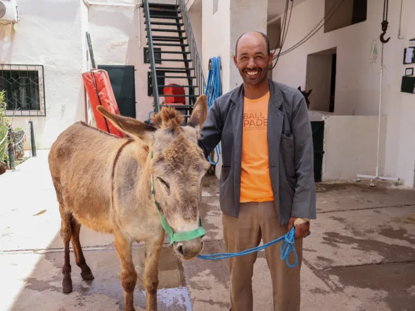 Smiling owner standing next to Maysa the donkey